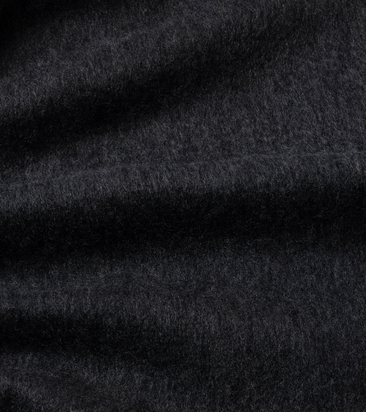 A close-up of dark charcoal gray textured fabric with soft folds and a fine, slightly fuzzy surface.