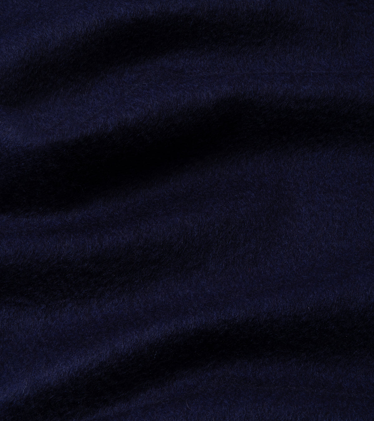 A close-up of dark navy blue plush fabric with soft folds and a textured, fuzzy surface.