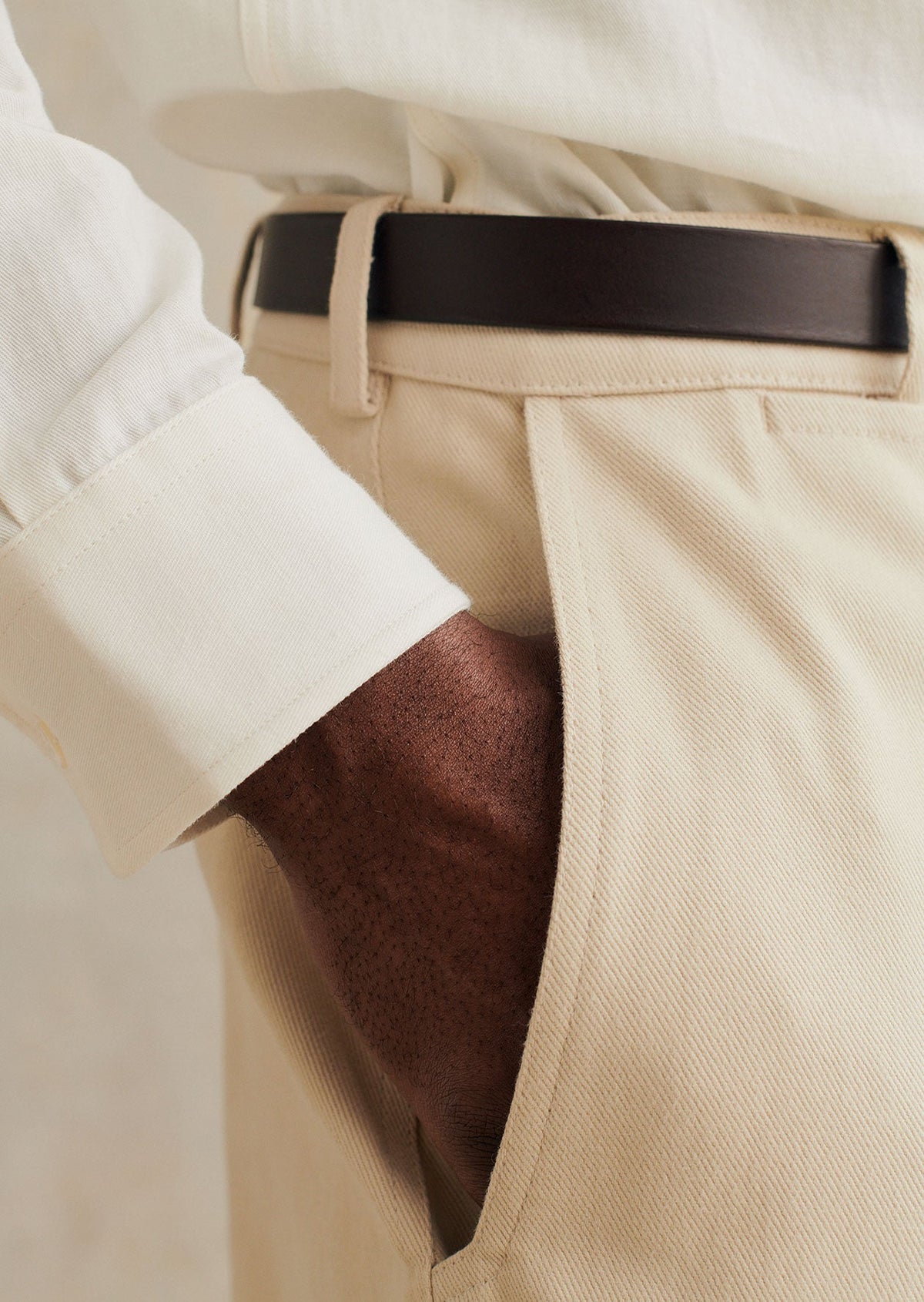 Close-up of the model wearing the De Bonne Facture Heavy Cotton Balloon Trousers in Cream styled with a leather belt and white shirt.