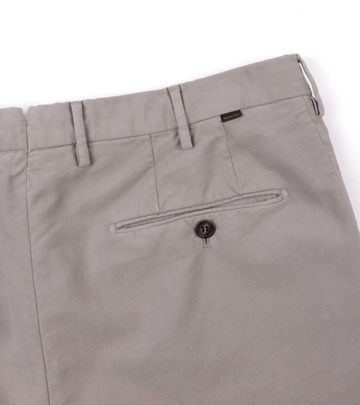 Back close-up of the Incotex Regular High Cotton Doeskin Trousers in Greige showing the waistband, belt loops, a rear welt pocket with a button closure, and a small brand tab near the waistband.