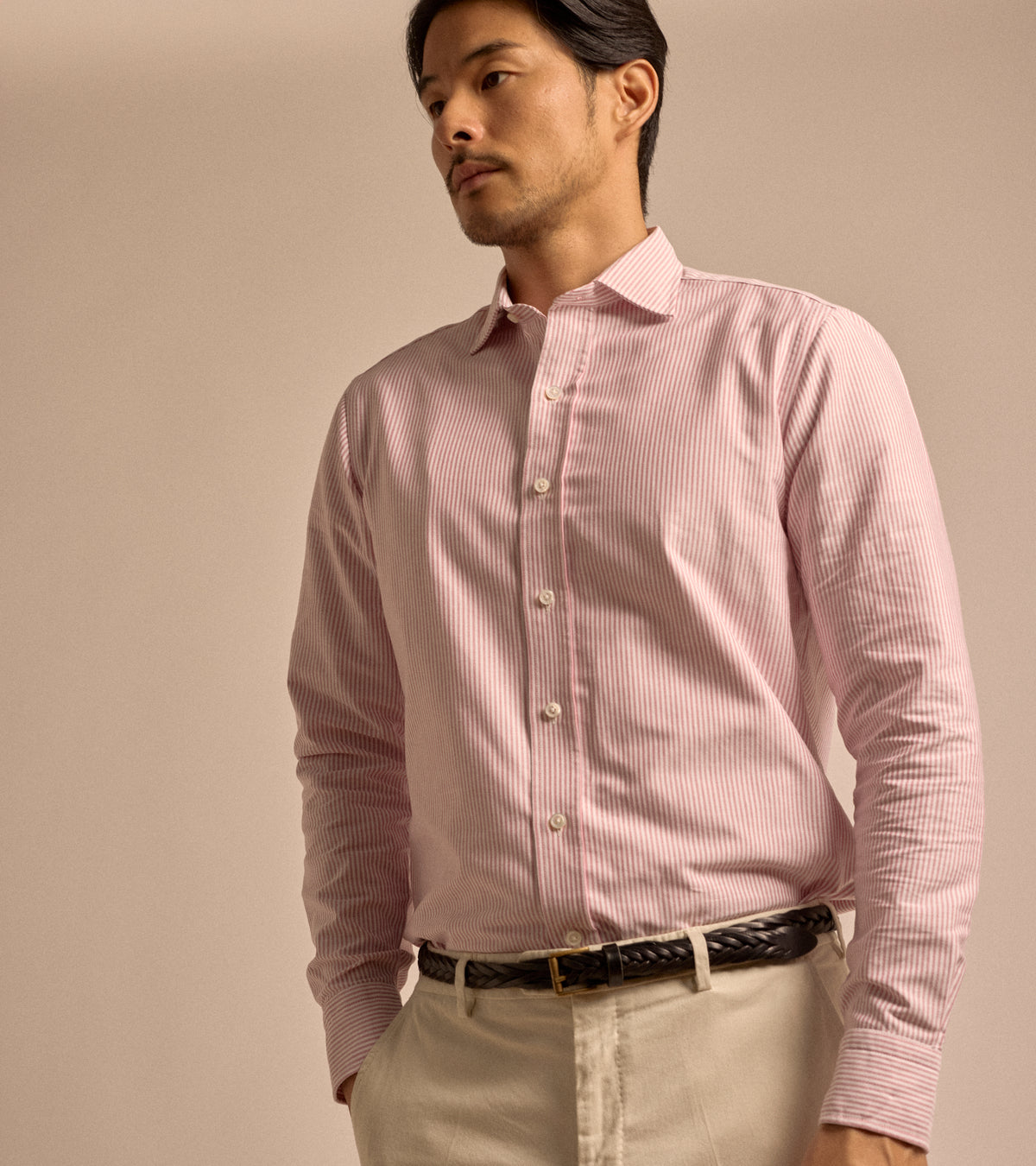 Model wearing the Salvatore Piccolo Striped Cotton Oxford Shirt in red, styled with a braided leather Anderson's belt and Trunk Palmer trousers in sand.