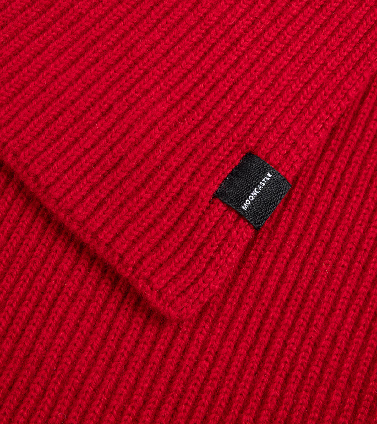 Close up of Mooncastle Cashmere Short Scarf in Red showing fabric and ribbed detail. Square Mooncastle label stitched.
