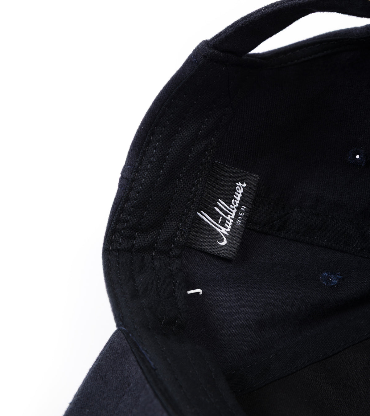 Close-up of the interior of the baseball cap, showing a black fabric brand label.