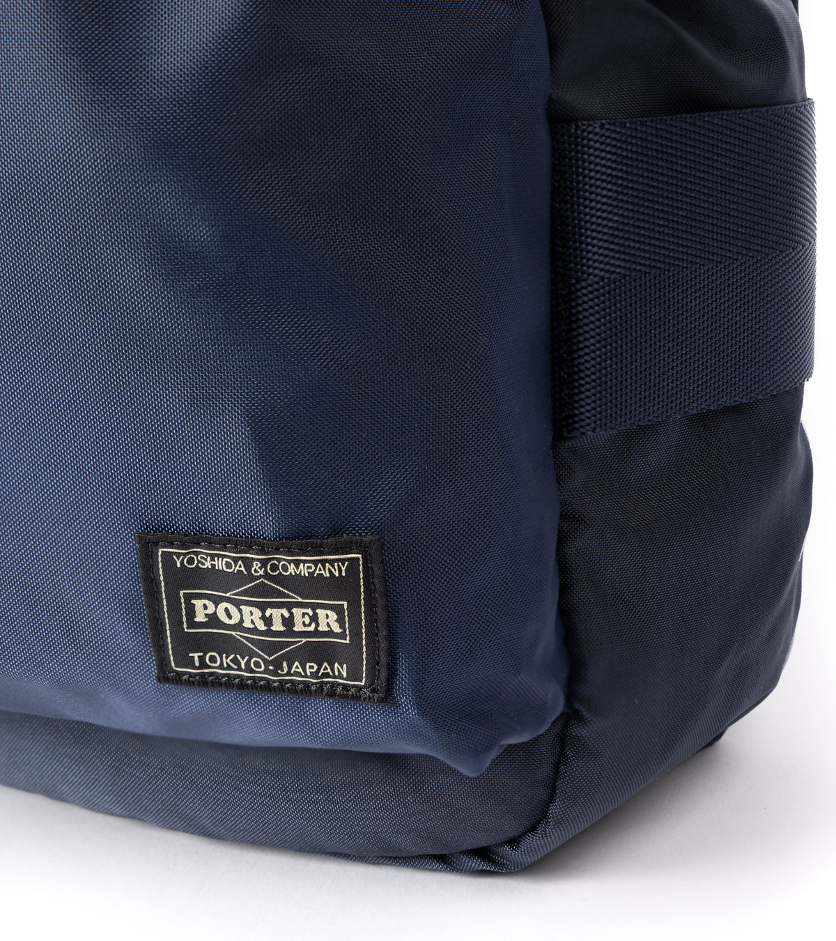 PORTER Force Shoulder Bag in Navy. Close-up detail of the Porter label and fabric.