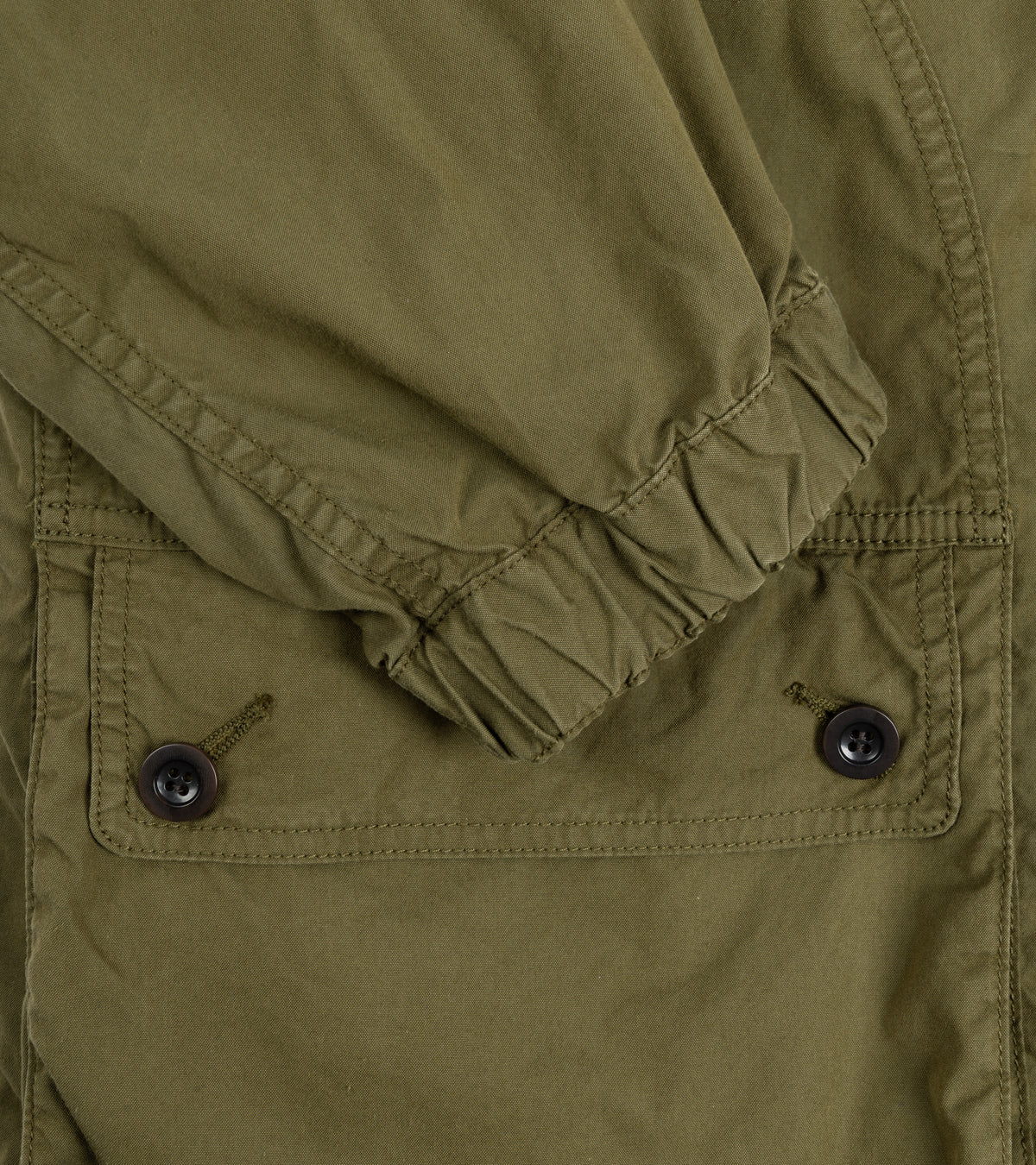 Sage de Cret Cotton Nylon Oxford Three-Way Work Jacket in Olive. Close-up detail of the sleeve with elasticated cuff and pocket flap with two button fastening.