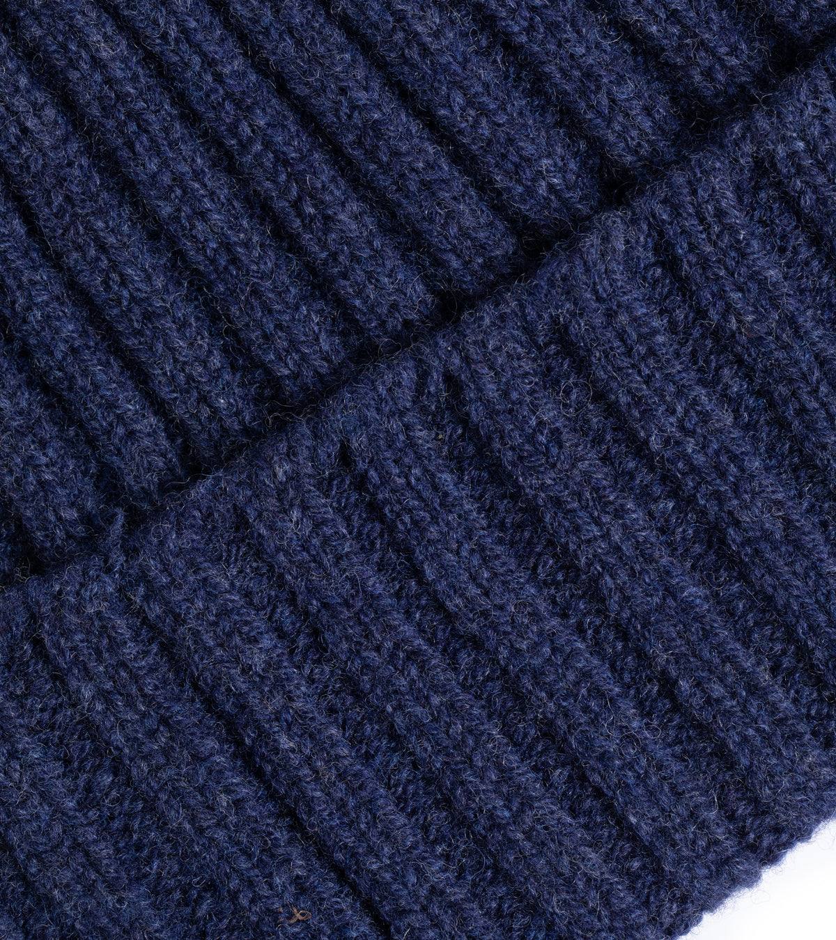 Trunk Lambswool Ribbed Beanie in Dark Blue showing the fabric texture, the detailed weave and folded pattern.