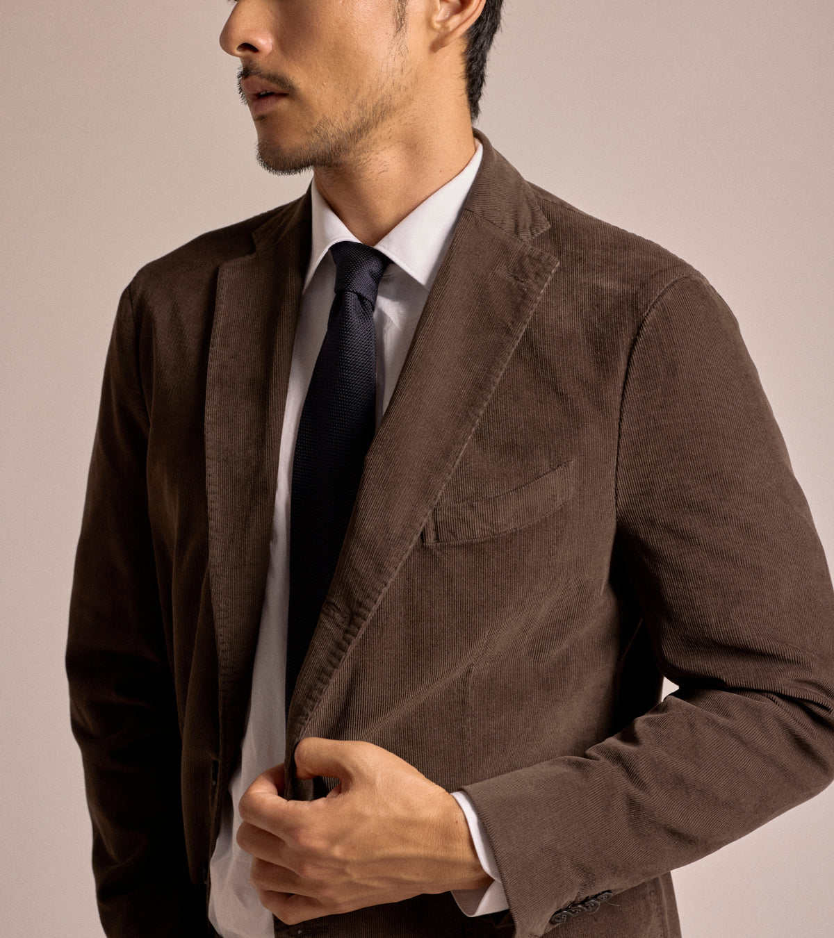 Model wearing the Boglioli Cotton Corduroy Suit Jacket in Brown over a white dress shirt and a dark navy tie, shown from the side.