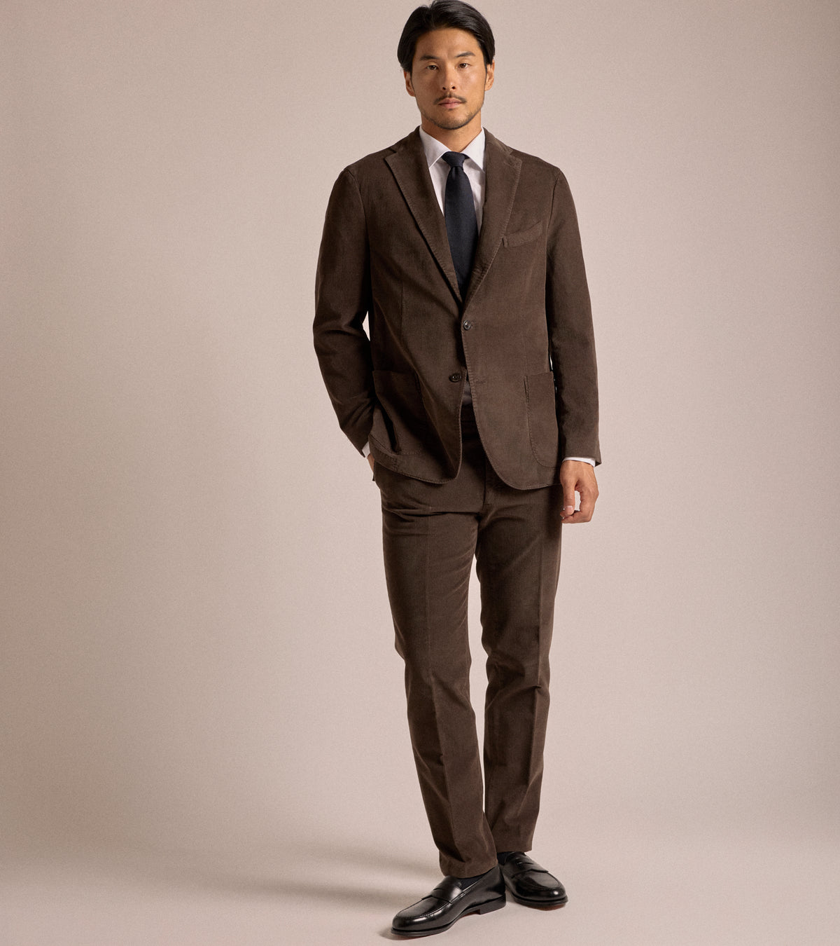 Model wearing the Boglioli Cotton Corduroy Suit Jacket in Brown styled with a white shirt, navy tie and matching trousers.