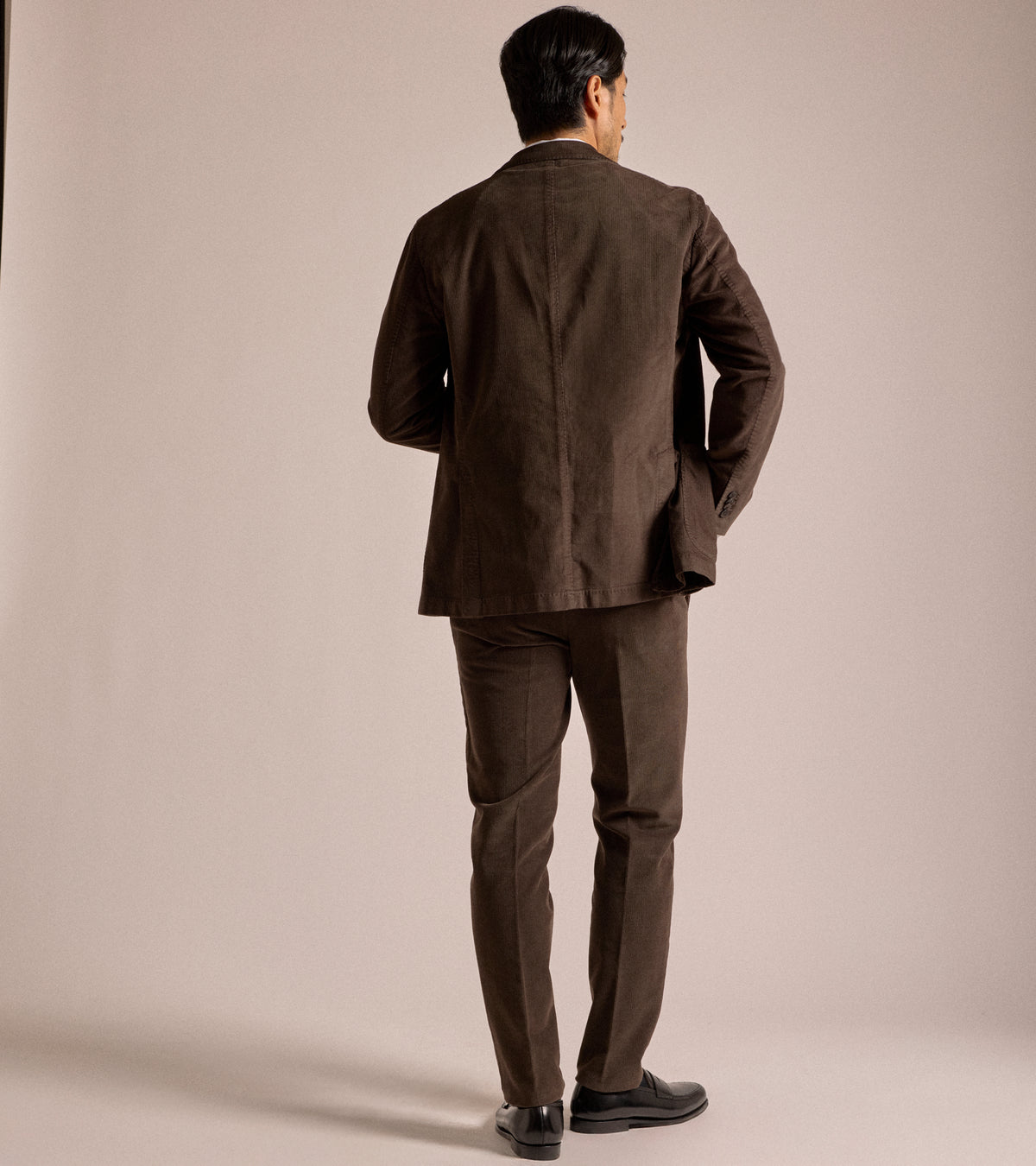 Back view of a model wearing the Boglioli Cotton Corduroy Suit Jacket in Brown paired with matching trousers.