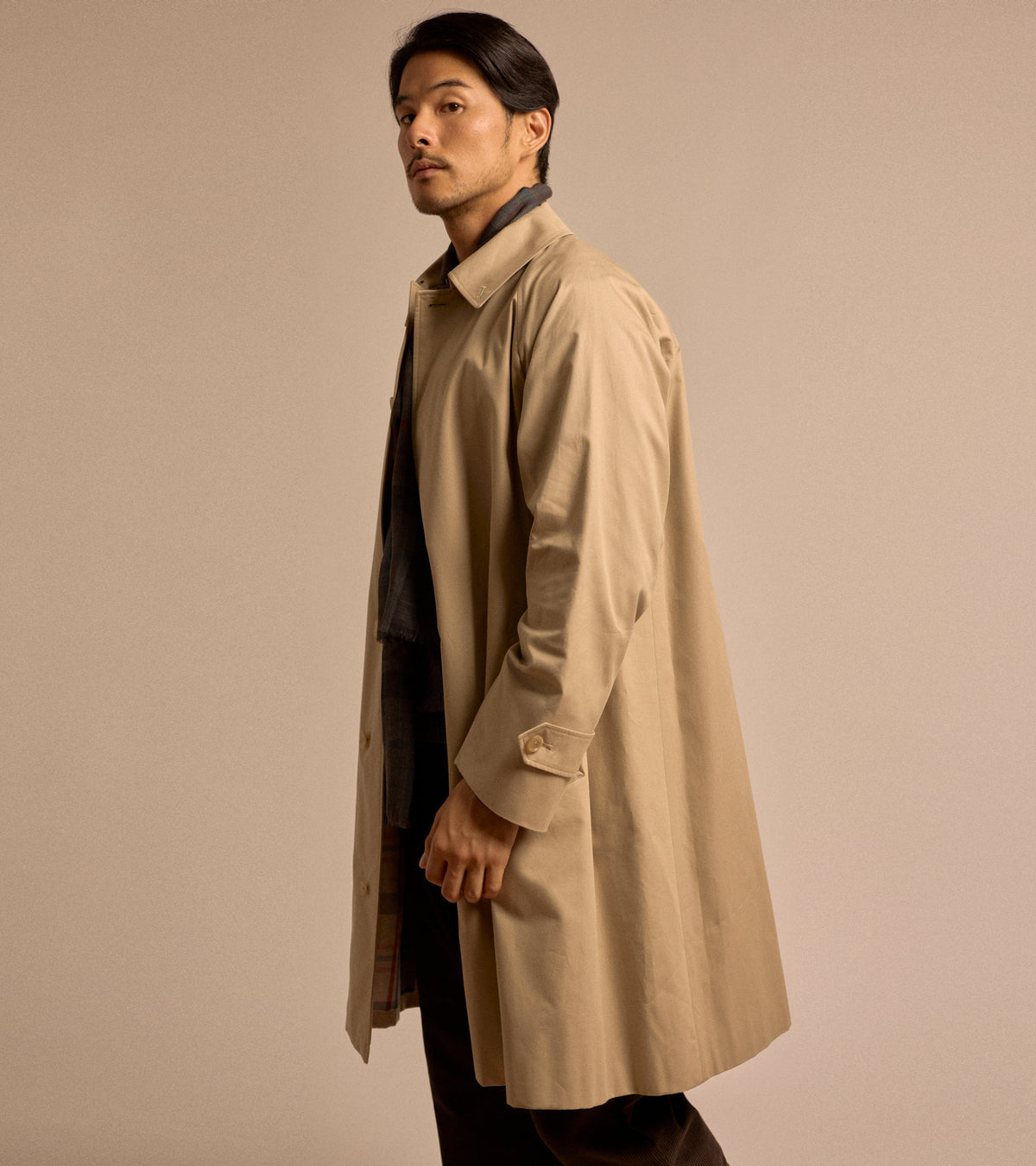 Model wearing the Sanyo 100 Year Lightweight Gabardine Balmacaan Coat in Beige. Shown here from a side view.