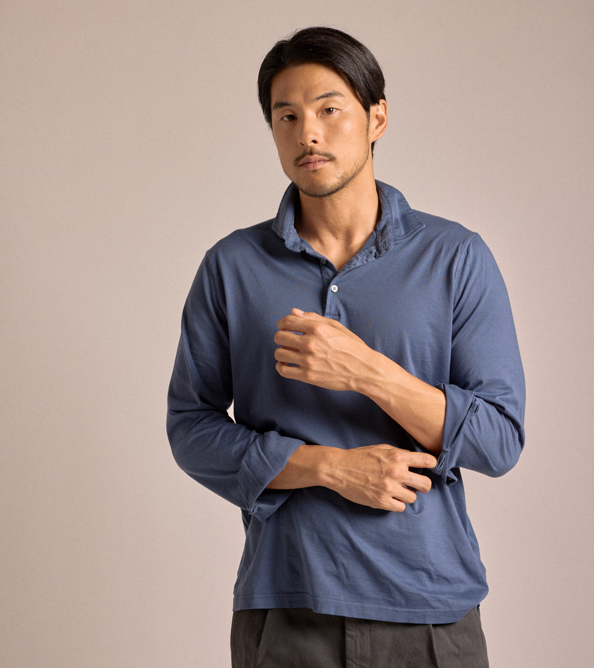 Model wearing the Fedeli Zero Cotton Jersey Long Sleeve Polo in Dark Blue. Front view with the top two buttons undone and the sleeves rolled up halfway.